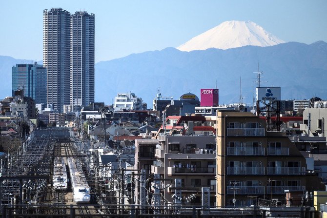 N700Aシリーズの2本の新幹線が、日本の最高峰で標高3,776メートル（12,388フィート）の富士山を遠く背景にあおいで、東京に発着している。（写真撮影チャーリー・トリバロー / AFP）