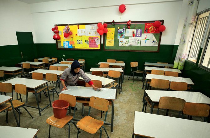 コロナウイルスの影響で閉鎖された学校で教室の机を掃除する作業員＝2020年2月29日、レバノン・シドン（ロイター通信）