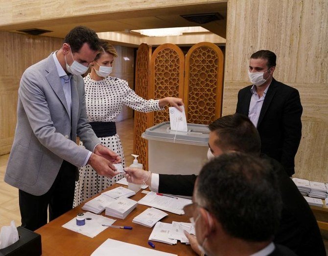 2020年7月19日、シリアのダマスカスで行われた議会選挙の投票所で票を投じるシリアのバシャール・アル・アサド大統領と、妻のアスマ夫人。（SANA/ロイター通信による配布資料）