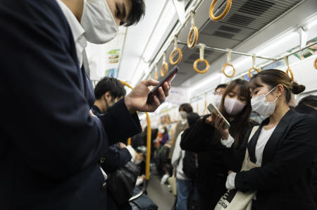 フェイスマスクを着用した人は、2021年4月14日(水)に西日本の大阪で電車に乗ります。(AP)
