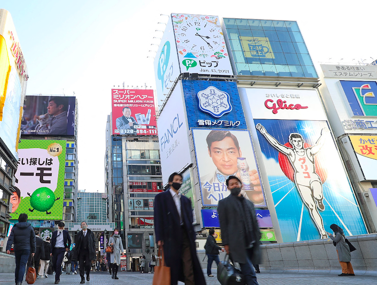 大阪府の繁華街にある有名な道頓堀地区で人々が通りを歩いている。（AFP）