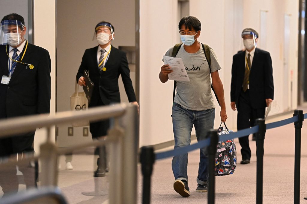 ミャンマーの軍事クーデターを取材中に治安部隊に逮捕された日本のジャーナリスト北角裕樹さん（2R）。外交的配慮により起訴取り下げとなり解放された後、千葉県成田空港に到着し記者会見を終えて空港内を歩く様子、2021年5月14日。（資料写真/AFP）