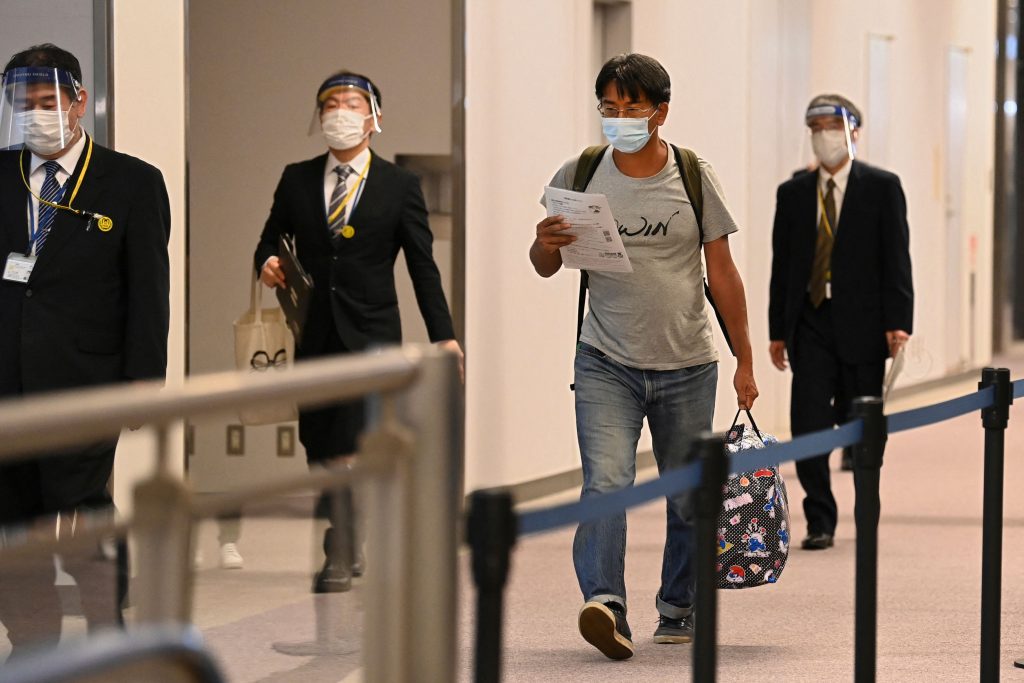 ミャンマーの軍事クーデターを取材中に治安部隊に逮捕された日本のジャーナリスト北角裕樹さん(2R)。外交的配慮により起訴取り下げとなり解放された後、千葉県成田空港に到着し記者会見を終えて空港内を歩く様子、2021年5月14日。(資料写真/AFP)