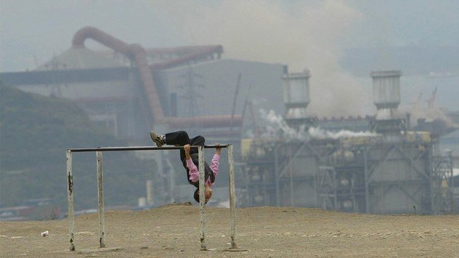 トルコのディロバシにある工場から発せられる大量の煙の中で遊ぶ子供。（写真：AFP 、2006年11月7日撮影）