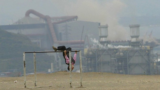 トルコのディロバシにある工場から発せられる大量の煙の中で遊ぶ子供。(写真:AFP 、2006年11月7日撮影)