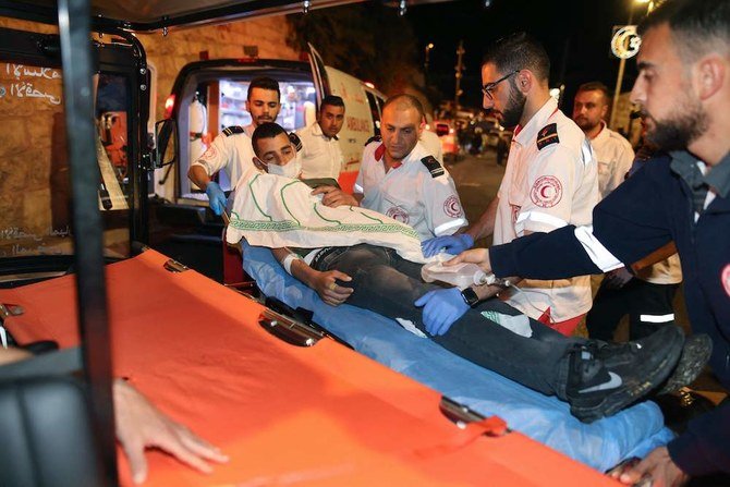 2021年5月7日、アル・アクサの複合型モスクでイスラエル警察との間で発生した衝突中に負傷したデモ参加者を搬送するパレスチナの医療関係者ら。（AFP通信）