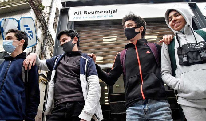 1954年から1962年のアルジェリア独立戦争中にフランス人に殺されたアルジェリア人弁護士を称えた、町の通りにある名前看板の下でポーズをとる、アルジェリア人の若者たち。(AFP通信 資料写真)