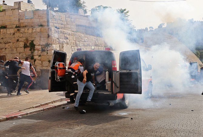 2021年5月10日、エルサレム旧市街でイスラエル治安部隊が催涙ガスを発射する中、パレスチナ人衛生兵が負傷した抗議者らを避難させている。（AFP通信）
