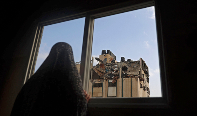 2021年5月11日早朝、ガザ市のアルシャティ難民キャンプでイスラエルの空爆により被害を受けた建物の屋根を見つめるパレスチナ人女性。（AFP）
