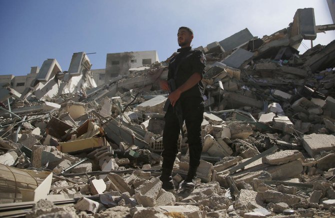 2021年5月15日土曜日、イスラエル軍用機が破壊したガザ市のAP事務所やその他メディアを収容する建物の瓦礫の上に立つ男性。(AP)