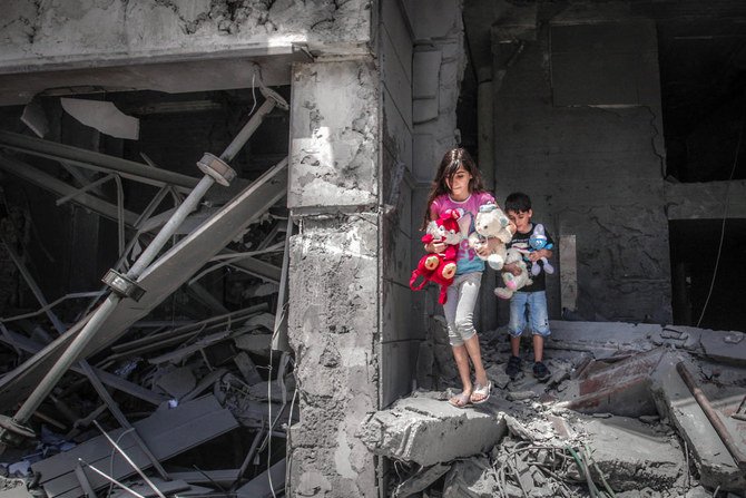 イスラエルの空爆で大きな損害を受けたガザ市のアル・ジャワラ・タワーで、自宅からおもちゃを回収するパレスチナの子どもたち。（アナス・ババ/AFP）
