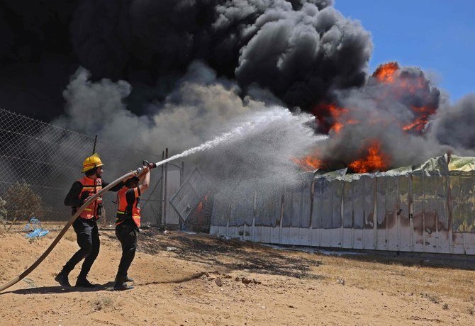 パレスチナ市民防衛隊の隊員が、火曜日にガザ南部でイスラエル軍の砲弾を受けたペンキ倉庫の火災を消火している（AP通信）