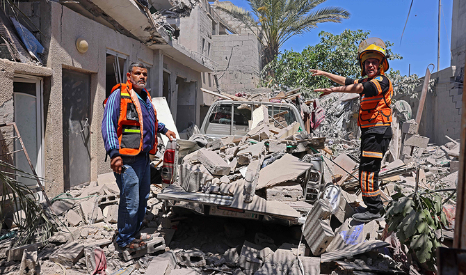 2021年5月18日、エジプトとの国境に近いガザ地区南部のラファで、イスラエルの空爆の標的となって破壊された住宅ビルの外で被害状況を調べるパレスチナの救助隊。(AFP)