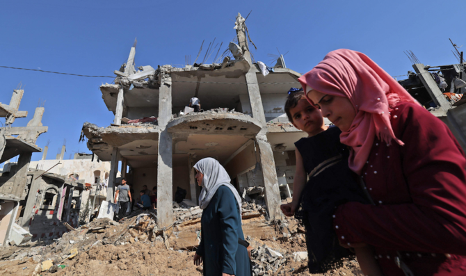 2021年5月21日、ガザ地区北部のベイトハヌーンで、イスラエルの空爆で破壊された建物の前を歩くパレスチナ人。（AFP通信）