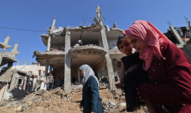 2021年5月21日、ガザ地区北部のベイトハヌーンで、イスラエルの空爆で破壊された建物の前を歩くパレスチナ人。(AFP通信)