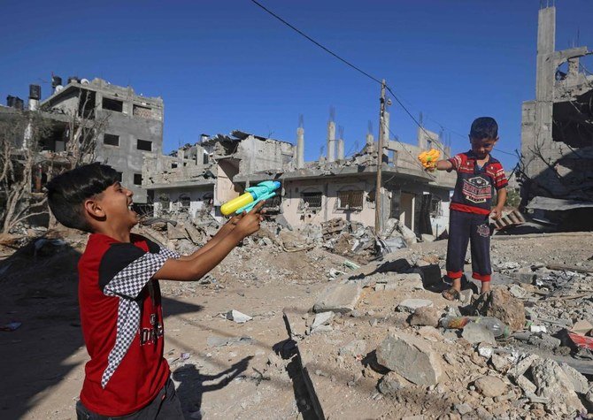 イスラエルの空爆により破壊されたガザの家の瓦礫の隣で、おもちゃの銃を持って遊ぶパレスチナの子どもたち。5月24日撮影。国連人権理事会は広範で国際的な調査の開始を検討する。（AFP）
