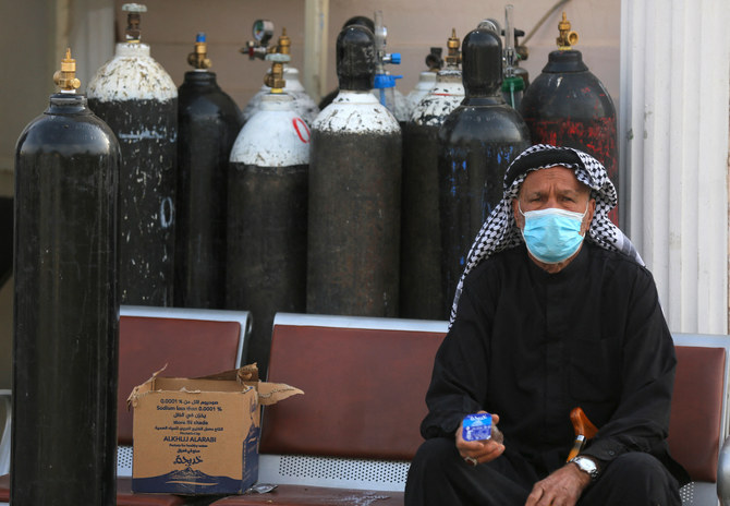 酸素ボンベの隣に座り新型コロナ患者の妻を待つイラク人男性、バグダッドのイブン・アルカティブ病院。（資料写真/AFP）