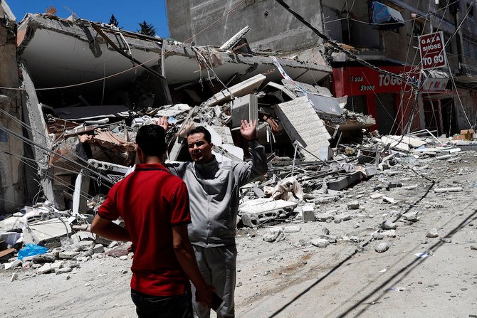 2021年5月13日（木）、ガザ市でイスラエル軍の空爆を受けて破壊された建物の跡の前で反応を見せるパレスチナ人（AP通信）