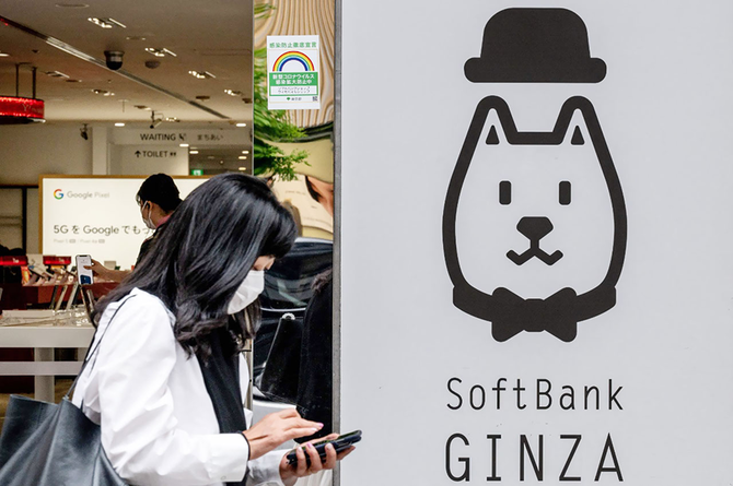 水曜、東京のソフトバンクグループのロゴの前を通り過ぎる女性。（AFP）