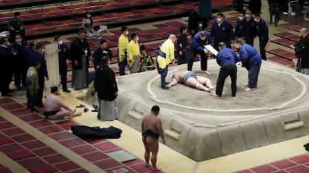 共同通信が報道したこの写真に、2021年3月26日、東京の両国国技館における大相撲中に力士の響龍（28）、本名天野光稀が土俵で倒れ、彼の周りに関係者が集まる様子が写る。（ロイター）