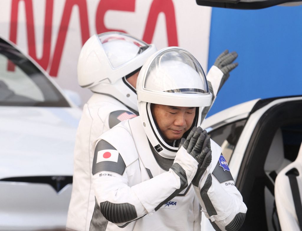 2020年11月15日、宇宙航空研究機構(JAXA)の宇宙飛行士、野口氏(右)とNASA の宇宙飛行士マイク・ホプキンス氏が、家族へ手を振りながらケネディ宇宙センターの運用点検施設を出てスペースXファルコン9ロケットへと向かっていく。ファルコン9は宇宙船クルードラゴンと共に発射台39Aに設置されている。(AFP)