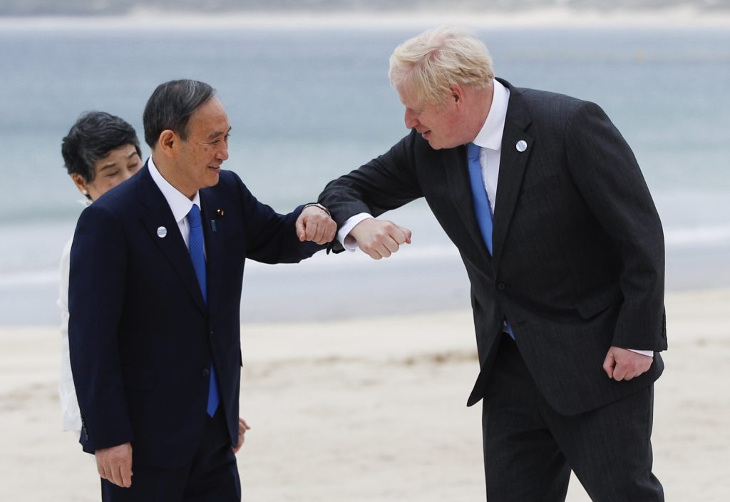 6月11日、英国コーンウォール州セントアイブス、カービスベイのカービスベイホテルで行われるG7首脳会議に到着する際、日本の菅義偉首相と真理子夫人に挨拶する、英国のボリス・ジョンソン首相。(ファイル写真:AP)