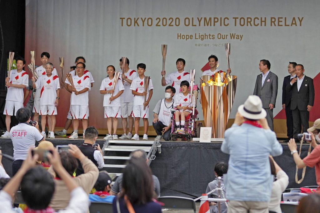 2021年6月29日、神奈川県相模原市で予定されていた公道での聖火リレーが中止となり、舞台上での写真撮影で一緒にポーズを取るオリンピック聖火リレーのランナーたち。（ファイル写真 / AFP）