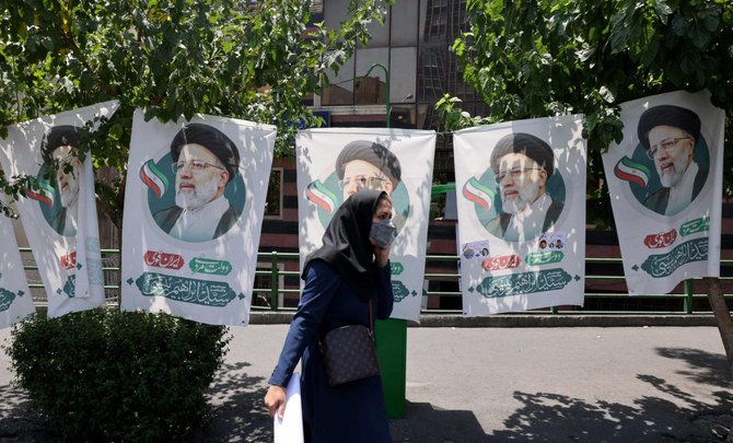 2021年6月17日のテヘランで、超保守派の聖職者および大統領候補であるエブラヒム・ライシ氏の旗の横を通り過ぎるイラン人女性。（AFP/ATTA KENARE）