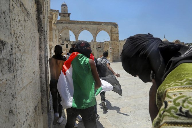 衝突でイスラエル軍に向かって投石を行うデモ隊員。エルサレム旧市街のアル・アクサモスク群にて。(AP)