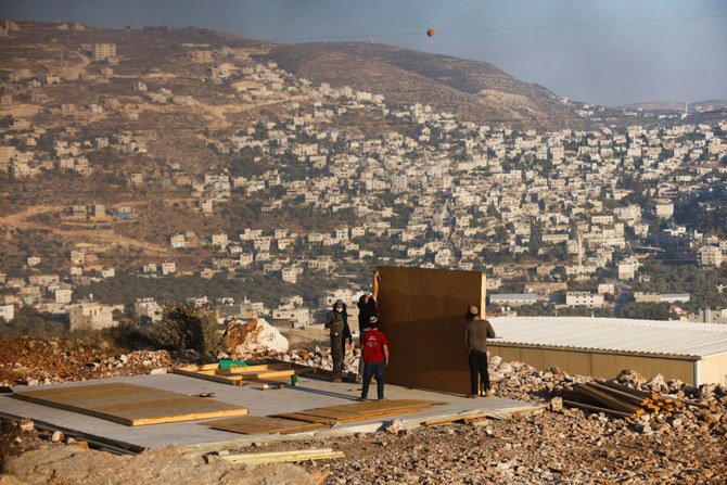 2021年6月23日、ヨルダン川西岸のパレスチナ人が住むベイタ村の近くにある、新しいイスラエルの辺境の入植地、ギバト・エビアタルで、ユダヤ人入植者の若者が建物を建てている。（ロイター通信/アミール・コーエン）