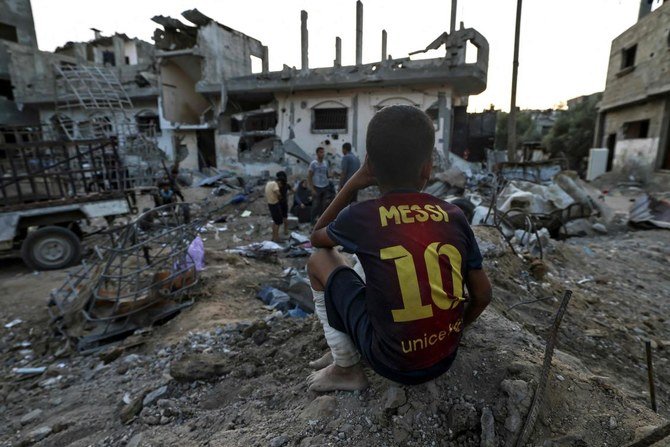停戦によって紛争が終わり1週間以上経った後、ガザ地区北部の破壊された建物の近くに座る少年。（資料画像/AFP）