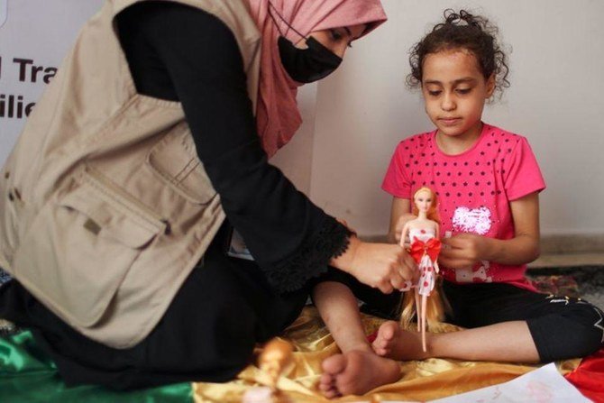 イスラエル - パレスチナ戦闘中のイスラエルによる空爆で破壊された自宅から助け出されたパレスチナ人少女スージー・イシュクンタナと遊ぶ心理学者（ファイル/ロイター）