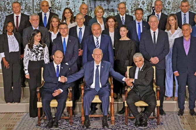 ナフタリ・ベネット首相（左）とヤイル・ラピド副首相兼外相（右）と並んで新政権発足の記念撮影に臨む、退任を控えたイスラエルのルーベン・リブリン大統領（中央）。（AFP）