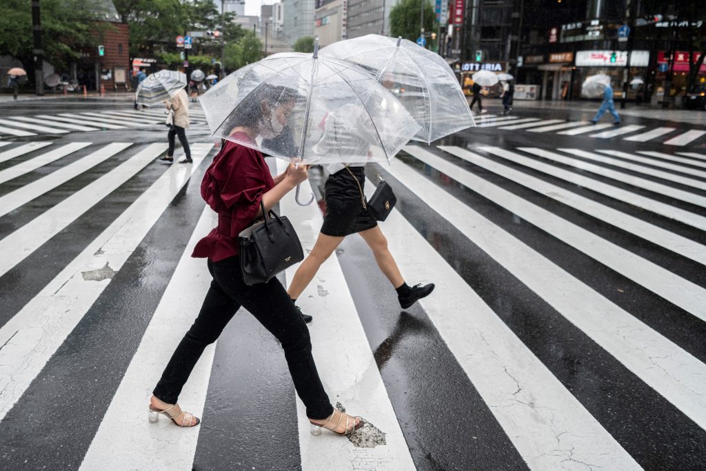 雨の日に道路を渡る女性たち。2021年6月4日、東京。（AFP）