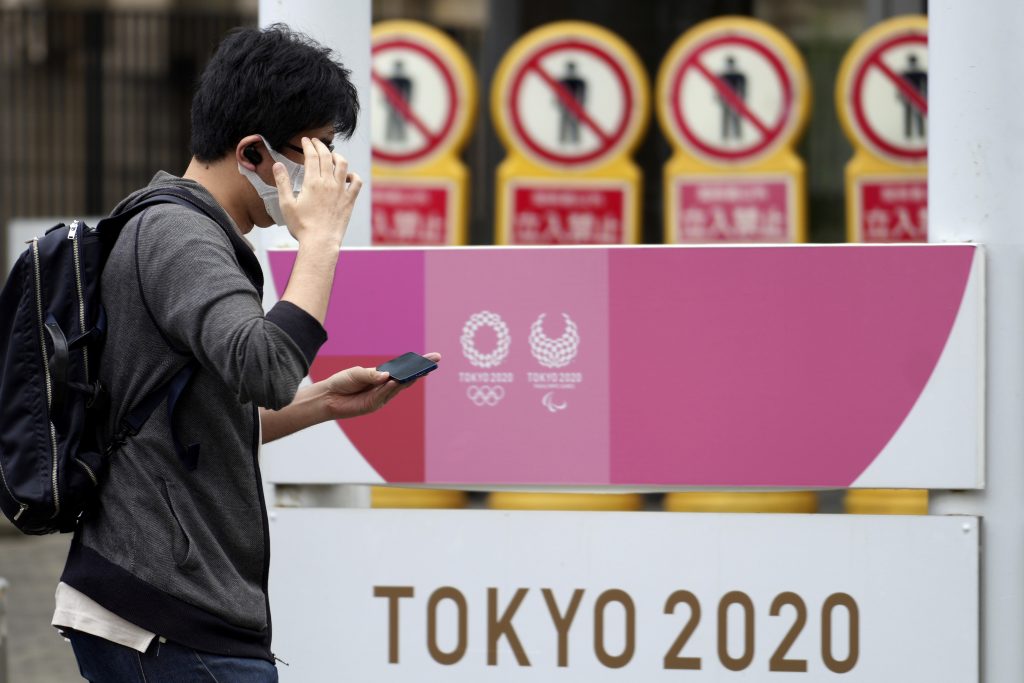 2021年6月29日火曜日、新型コロナウイルスの蔓延を抑えるためにマスクを着用し、都内にある東京オリンピック・パラリンピック2020の広告の近くを歩く男性。(AP写真 / Eugene Hoshiko)