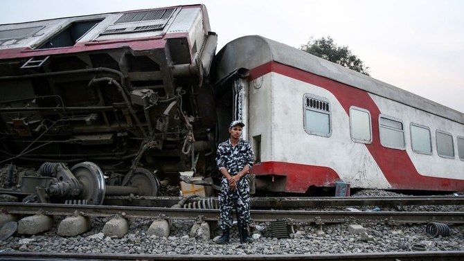 2021年4月18日、カリウビヤの鉄道事故の現場で、横転した客車の前で警備にあたるエジプト治安部隊の隊員。（AFP通信）