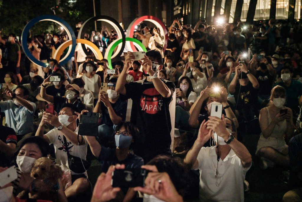 2021年7月23日、東京の国立競技場の隣りで東京オリンピック2020大会開会式の際に打ち上げられた花火を見る人々。(AFP)