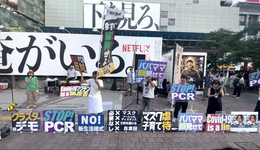 Covid-19に反対する抗議者は、東京の混雑した渋谷スクランブル広場に集まり、PCRテストに反対するプラカードを掲げ、マスクは「嘘」だと。(ANJの写真)
