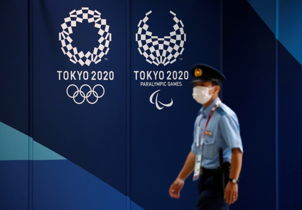 メインプレスセンターの東京2020オリンピックの看板を通り過ぎる警官。2021年7月13日、日本、東京。ロイター／エドガー・スー