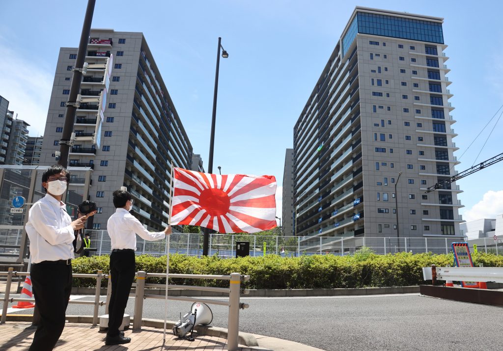 日本の戦時中の軍国主義の象徴とされる旭日旗を掲げ、韓国のオリンピック選手団が掲げた朝鮮の伝説的将軍李舜臣の有名な言葉を引き合いに出した横断幕に抗議する集会を催す日本の右翼集団のメンバー。日本、東京のオリンピック選手村にて、2021年7月16日。(File photo/EPA)
