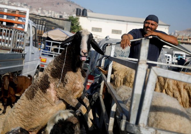 2021年7月15日、イスラエル占領下にある西岸のナーブルスで、イスラムの祝日イード・アル=アドハーに先立ち買い物するパレスチナの人々の中、市場で家畜の横に立つ男性。（ロイター）