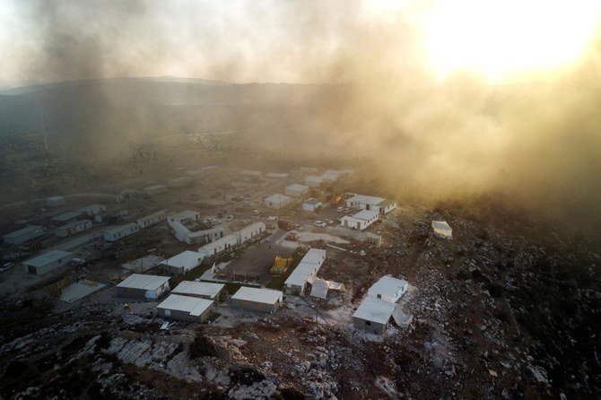 イスラエルが占領するヨルダン川西岸地区で、パレスチナの村ベイタで燃やされた火からのぼる煙が上方に漂う中、イスラエル人入植者の新しい前哨地であるギヴァット・エヴィアタルを上空から撮影した写真。(ファイル/ロイター)