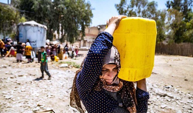 水の供給が途絶えたハサカで、ユニセフが提供した水の容器を運ぶシリア人女性。（AFP通信）