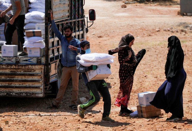 2021年6月9日、シリアの反体制派が支配するイドリブ県で、人道支援物資の箱を運ぶ作業員。(ロイター通信/Khalil Ashawi/写真)