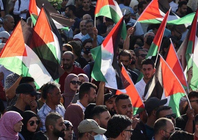 2021日7月11日、占領下にあるヨルダン川西岸地区のラマッラー市で、パレスチナ人のデモ抗議者たちが国旗を掲げている。（AFP）