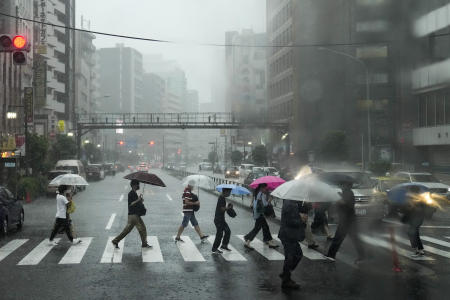 2021年7月11日(日)、東京で大雨の下で通りを横断する人々。東京2020オリンピックは2週間足らずで開幕する予定。(AP)
