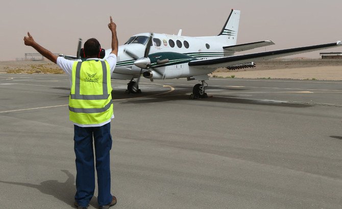 2015年4月23日にUAEのアル・アイン空港で、クラウドシーディングの任務に向けて飛び立つ準備をする双発のビーチクラフト機に合図を送る空港従業員。（AFP）