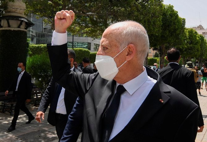 チュニスのブルギバ通りを歩きながら、沿道の人に拳を上げてみせるチュニジアのサイード大統領。2日、大統領は相次ぐ解任劇に新たに駐米大使を追加した。(AP)