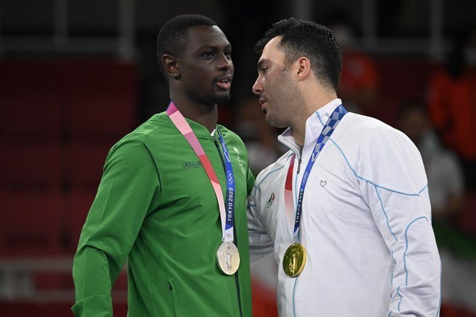 空手競技の男子空手75kg超級で銀メダルを掛けたサウジアラビアのタレグ・ハメディ選手と話す金メダルを首にしたイランのサジャド・ガンジュザデ選手（R）。（AFP）
