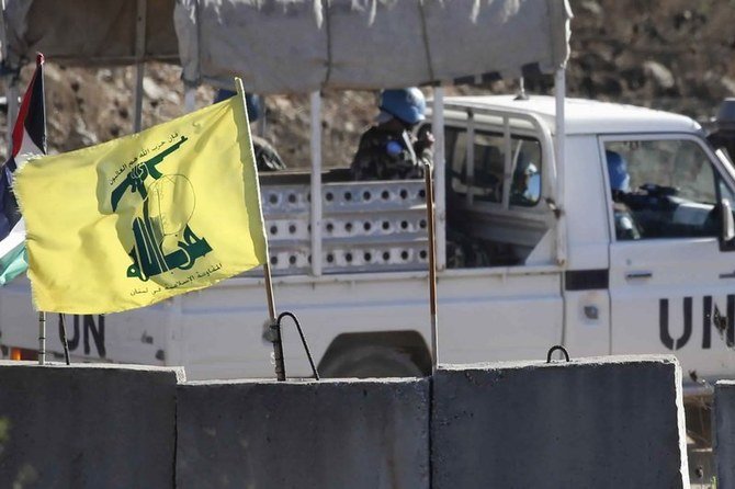 国連のパトロール車両が、イスラエル・レバノン国境のレバノン側にあるヒズボラの旗の前を通り過ぎる。（AP写真）